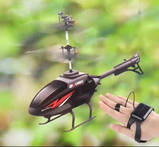 Black RC helicopter with remote control held by a hand against a blurred green background