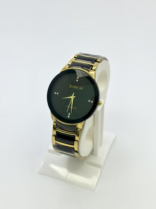 Watch with black and gold band on a white stand