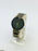 Watch with black and gold band on a white stand
