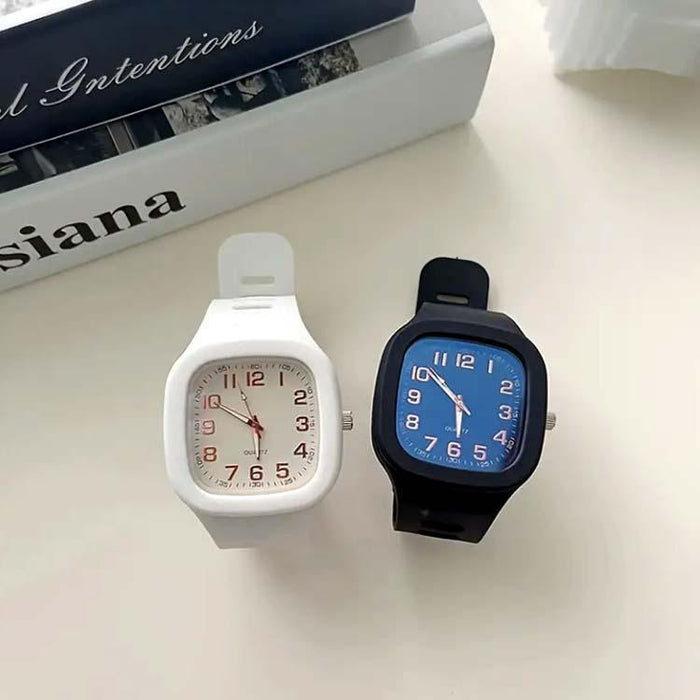 Two watches, one white and one black with blue face, on a light surface.
