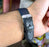 Black leather watch strap on a wrist with a blurred background