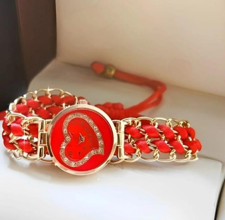 Red bracelet with gold chain and heart design on a white surface