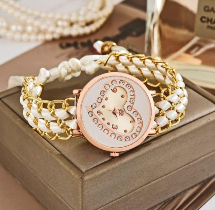 Decorative watch with white braided strap and gold accents on a wooden surface