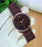 Brown Emporio Armani watch on a white glove with a blurred background