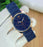 Blue watch with a gold case on a white surface