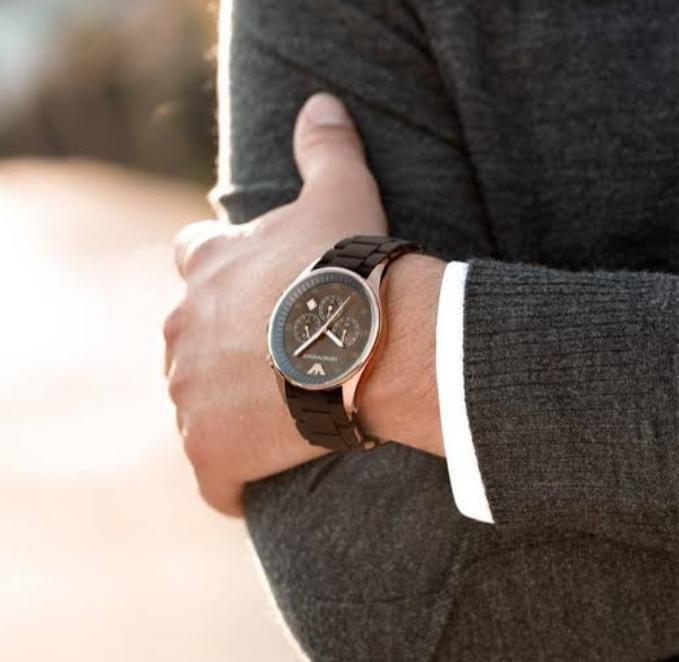 Person wearing a dark brown watch with a blurred background