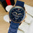 Blue watch with a gold case on a white glove against a wooden background