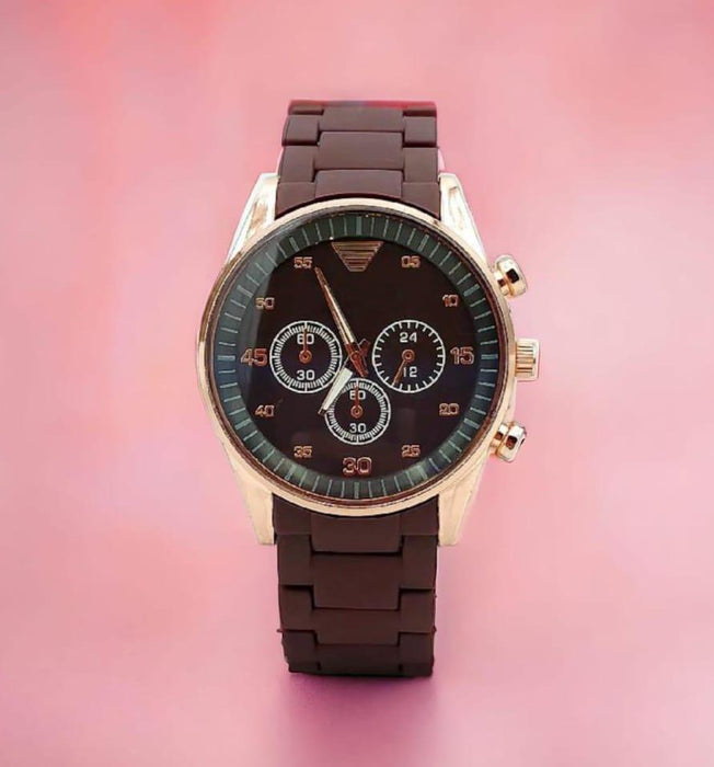 Watch with a brown strap and black face on a pink background