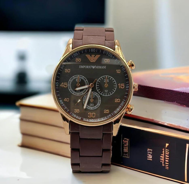Brown Emporio Armani watch on a stack of books with a blurred background