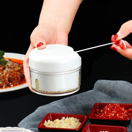 Person using a small white container with a spoon, surrounded by food on a dark surface.