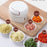 White handheld food chopper on a wooden cutting board with various chopped ingredients in small bowls.