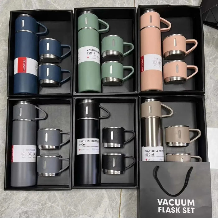 Set of vacuum flasks and cups in a packaging box on a gray surface.