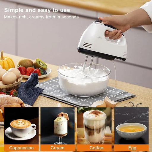 Hand mixer whipping cream with a bowl on a kitchen counter, surrounded by fruits and pastries.
