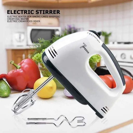 White electric hand mixer with attachments on a kitchen counter with vegetables in the background