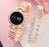 Rose gold digital watch with diamond-studded band on a pink background