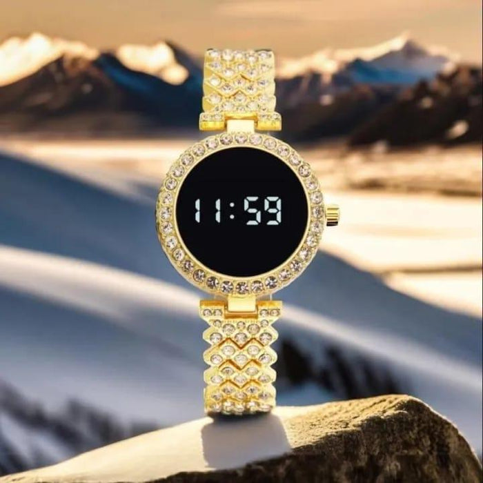 Gold digital watch with diamond-like accents on a rock with a mountainous background