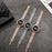 Three digital watches with gold, silver, and rose gold braided bracelets on a dark surface.