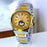 Gold and silver watch on a white surface with a blurred background