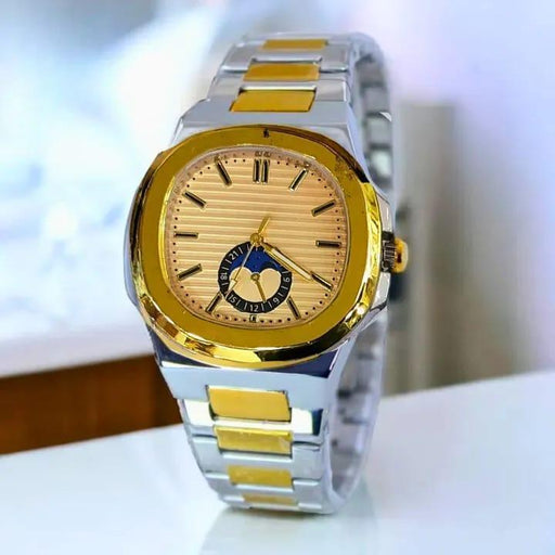 Gold and silver watch on a white surface with a blurred background