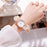 Hand wearing a watch with a marble-like strap on a blurred background