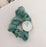 Green scrunchie with a watch face on a light background