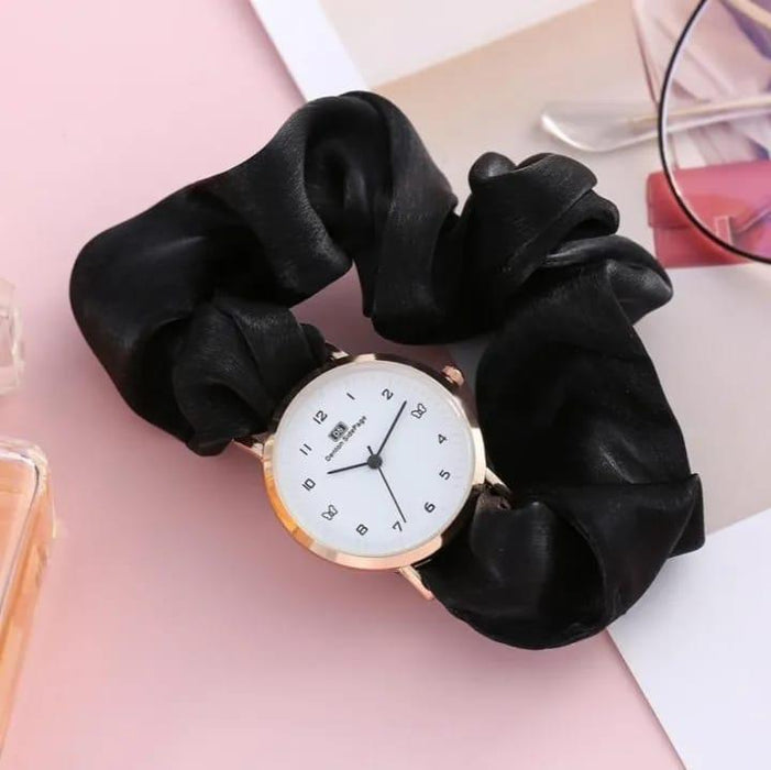 Black scrunchie with a watch face on a pink surface