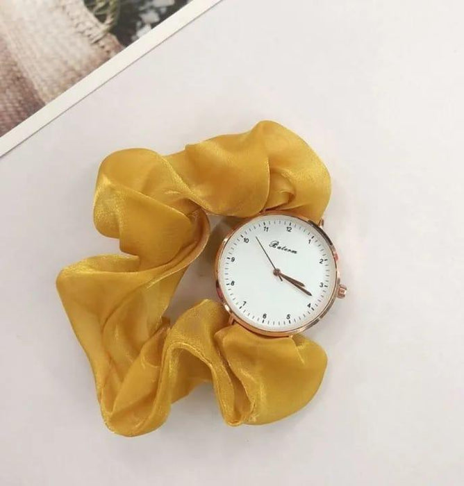 Yellow scrunchie with a watch face on a white surface
