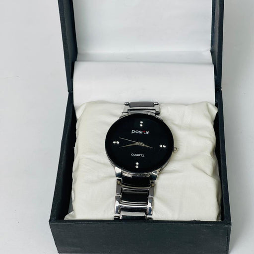 Black wristwatch with silver band in an open black box on a white background