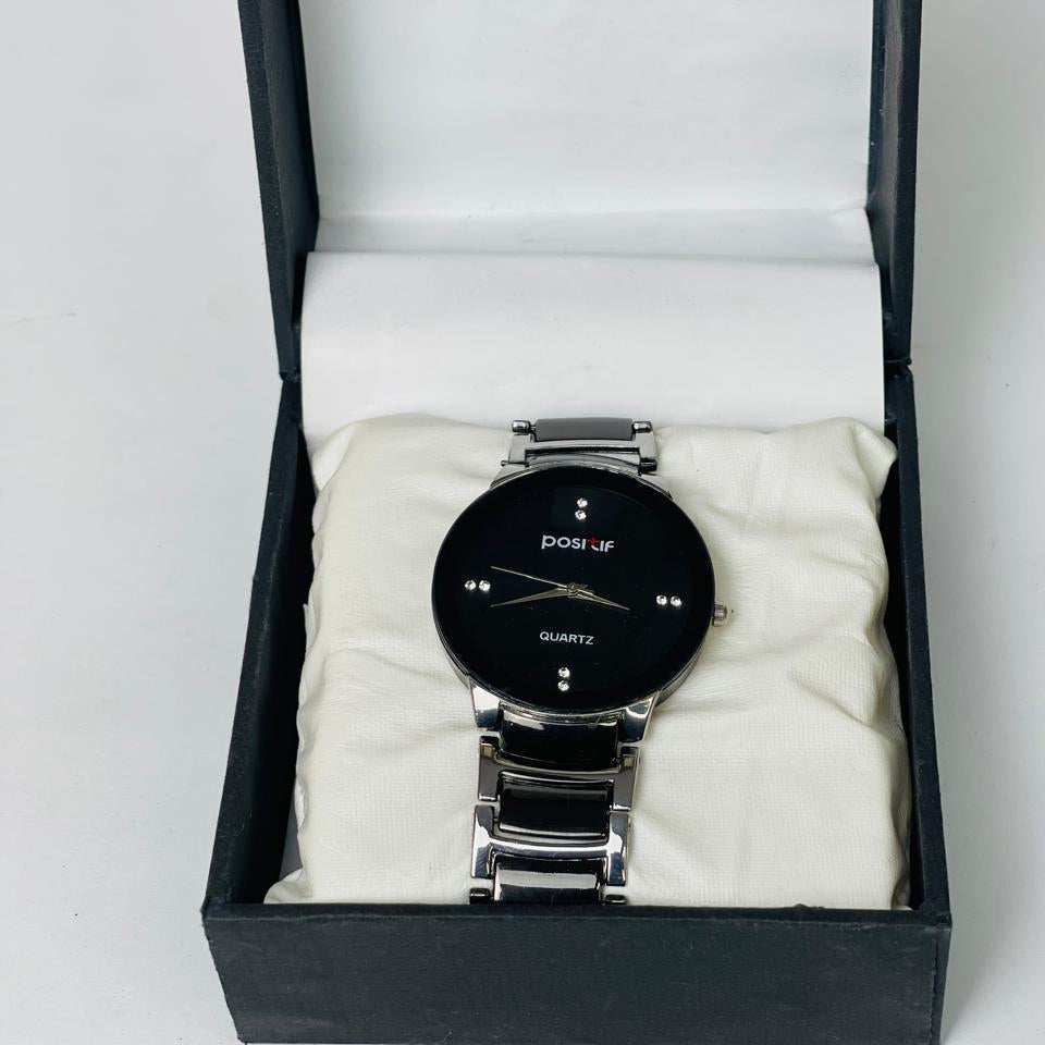 Black wristwatch with silver band in an open black box on a white background