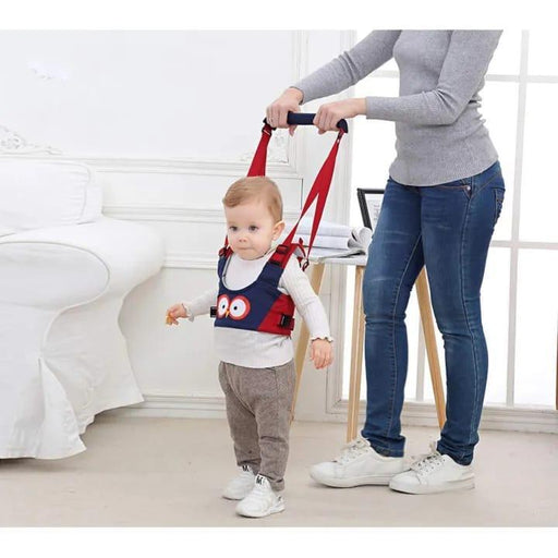 Child using a red and black walker with an adult holding it, in a home setting.