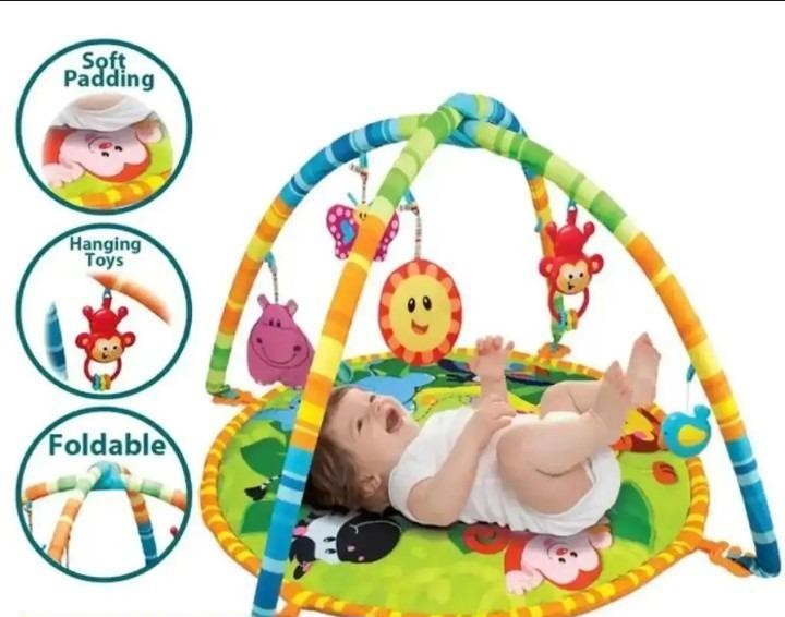 Baby play gym with hanging toys and soft padding, featuring a baby lying on it.