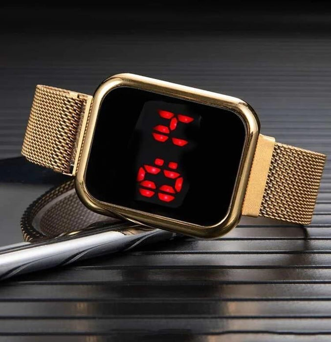 Gold digital watch with red display on a dark surface