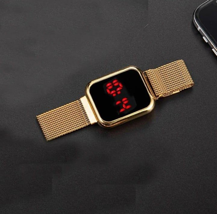 Gold digital watch with a black screen displaying red numbers on a dark surface.