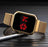 Gold digital watch with red display on a dark surface