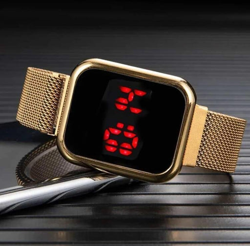 Gold digital watch with red display on a dark surface